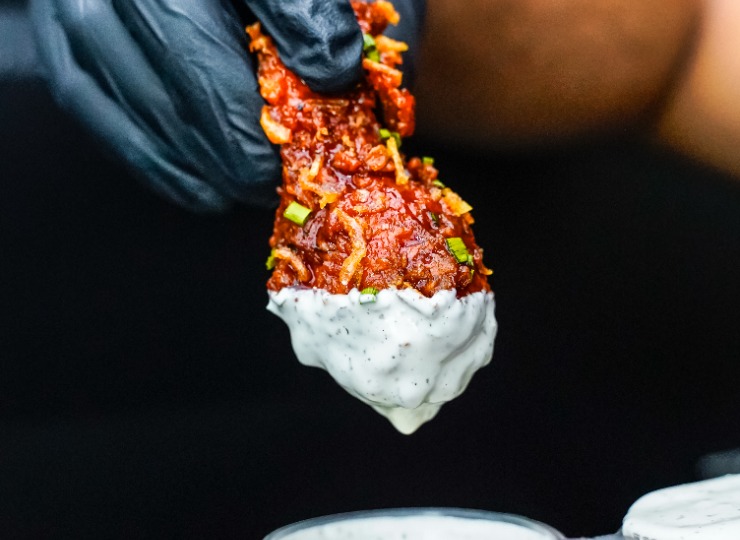 chicken wing smothered in sauce dipped into a sour cream sauce
